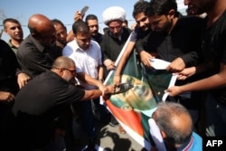 Iraqi men use a shoe to hit a picture of Turkish President Recep Tayyip Erdogan as they gather outside the Turkish consulate in the southern city of Basra to protest against the continued presence of Turkish troops in northern Iraq on October 14.