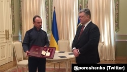 Ukrainian President Petro Poroshenko (left) presents a Hero of Ukraine award for Reshat Ametov to his brother in March 2018.