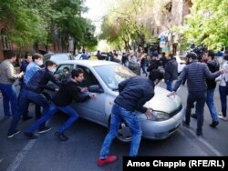 Protesters in Yerevan push a taxi after it tried to move through the crowd.