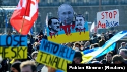 A protester holds up a sign with pictures of Russian President Vladimir Putin, Adolf Hitler, and Joseph Stalin, during an anti-war demonstration in Hamburg on March 20.