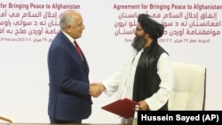 U.S. envoy Zalmay Khalilzad (left) and Mullah Abdul Ghani Baradar, the Taliban's top political leader, shake hands after signing a peace agreement in Doha on February 29.