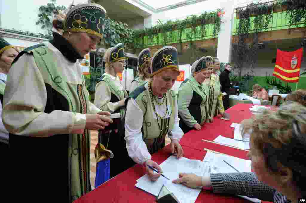 Wearing their traditional Russian costumes, members of a folk group receive ballots at a polling station in the village of Koshchino, outside Smolensk.