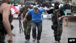 Members of the Vostok Battalion, a pro-Russia militia, escort an activist of the so-called People's Republic of Donetsk after detaining several of them following their storming of the regional state building in the eastern city of Donetsk on May 29.