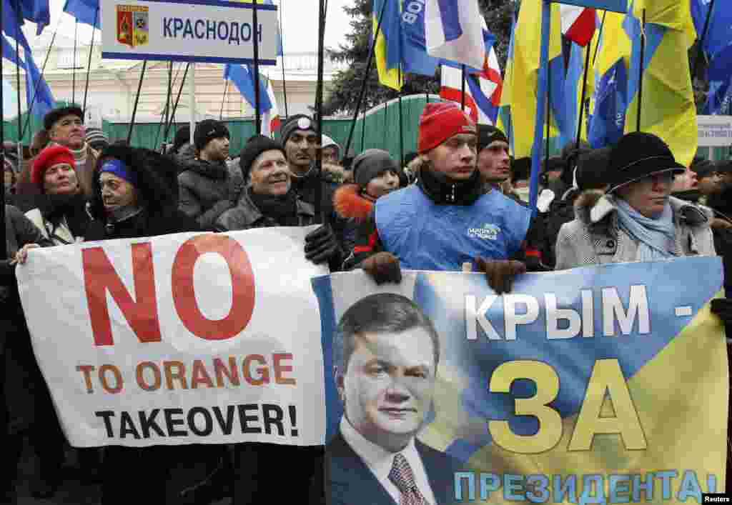 Supporters of Ukranian President Viktor Yanukovych hold flags and placards.