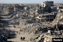 Palestinians walk past the rubble of houses and buildings destroyed during the war, following a cease-fire between Israel and Hamas, in Rafah in the southern Gaza Strip