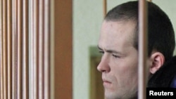 Former Belarusian opposition campaigner Vasil Parfyankou looks out from a cage in a courtroom in Minsk.