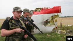 Armed pro-Russian militants in eastern Ukraine walk past next to the wreckage of Malaysia Airlines flight MH17.