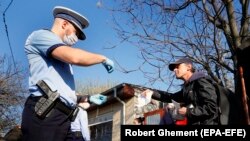 A Romanian police officer checks the travel documents of a man on the southern outskirts of Bucharest on April 3.