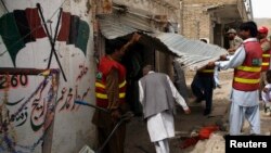 Police officers and rescue workers are seen at the entrance of damaged election campaign offices belonging to the Pakistan Peoples Party (PPP) after a bomb blast in Quetta on May 10.