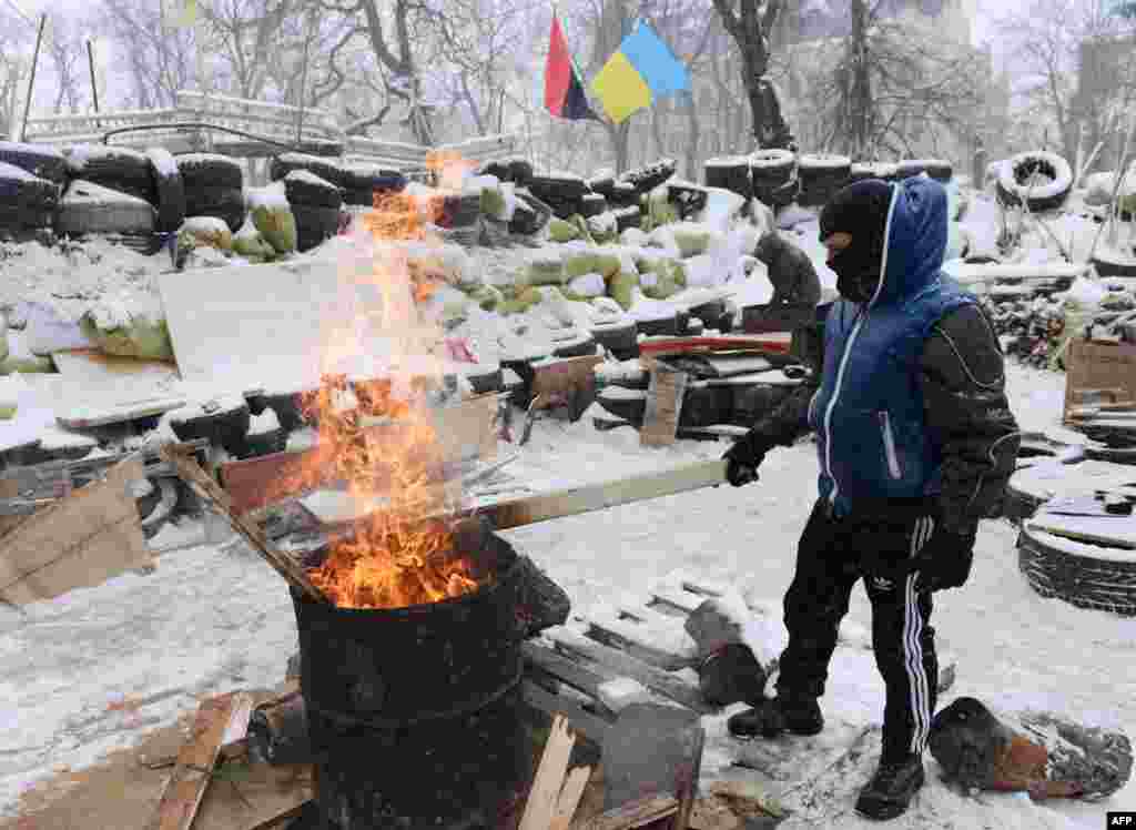 A protester warms himself near a fire at a barricade close to the regional administration building in Lviv.