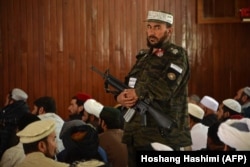 A Taliban fighter stands guard as Afghan men offer Friday prayers at the Wazir Akbar Khan mosque in Kabul in September.