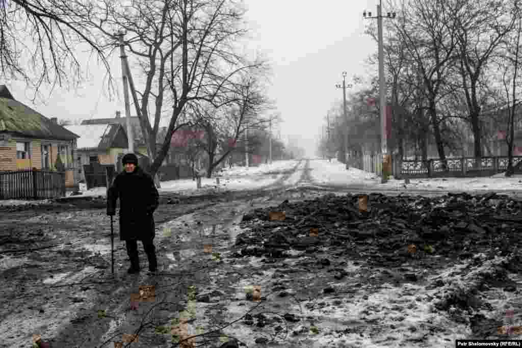 Valentina Pavlovna walks past a crater left by recent shelling as she goes to visit her sick aunt.