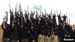 Islamist fighters hold up their weapons during their graduation ceremony at a camp in Syria, near Damascus, in November 2013.