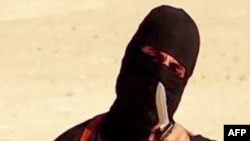 A masked, black-clad militant, who has been identified as a Briton named Mohammed Emwazi, brandishes a knife in this still file image from a 2014 video obtained from SITE Intel Group. 