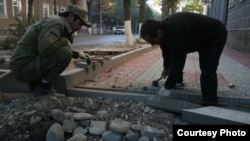 Two men repair a sidewalk in Tskhinvali, in South Ossetia.