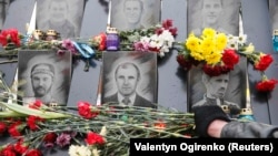 A person lays flowers during a commemoration ceremony at the monument to the so-called "Nebesna Sotnya" (Heavenly Hundred), the people killed during the mass pro-EU protests in 2014 in central Kyiv on February 20.