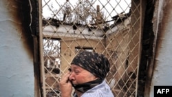 An ethnic Uzbek woman cries as she passes by a burned-out house in the town of Osh on June 24.