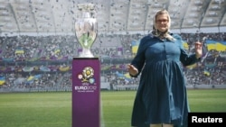 A Ukrainian woman poses for pictures next to the Euro 2012 trophy during a display to the public in central Kyiv on May 12.