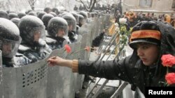 A woman places carnations into shields of antiriot police in Kyiv, November 2004