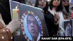 People hold candles in front of a portrait of the Sri Lankan worker who was lynched by a mob over allegations of blasphemy in Lahore in December.