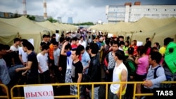 People who were detained during police raids on Moscow markets stand in a tent camp for illegal migrants in Moscow on August 5.