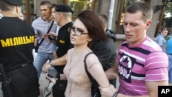 A woman is detained by Belarusian plainclothes policemen during one of the weekly protests against the regime in July.