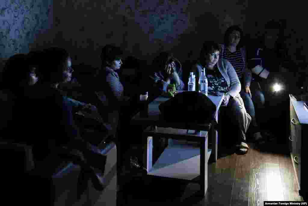 People watch state TV as they gather in a bomb shelter to protect against shelling in Stepanakert, the capital of the breakaway region of Nagorno-Karabakh. Nagorno-Karabakh authorities reported that shelling hit Stepanakert and the towns of Martakert and Martuni. (Armenian Foreign Ministry via AP)