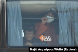 Afghans look out a a bus at the Dowqarun border crossing between Iran and Afghanistan in late August 2021.