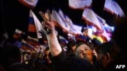 A Crimean man makes the "victory" sign as he celebrates on Simferopol's Lenin Square after polling stations closed in the Ukrainian republic on March 16.