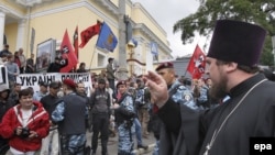 An Orthodox priest blesses demonstrators protesting against Patriarch Kirill's visit to Ukraine.