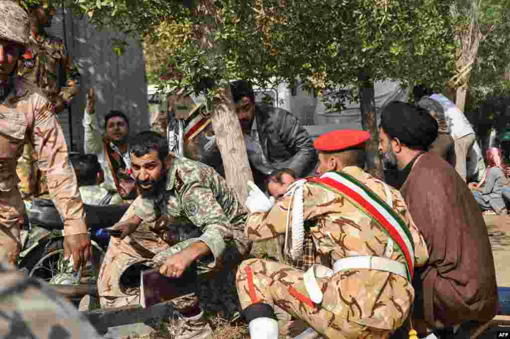 Soldiers and a Shi&#39;ite Muslim cleric (right) sitting close to the ground seeking cover at the scene of the attack.