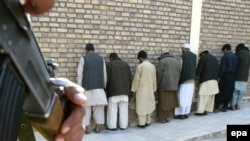 An Afghan security official stands guard over captured suspected Taliban militants. The government has somestimes used go-betweens to reach out to insurgents.