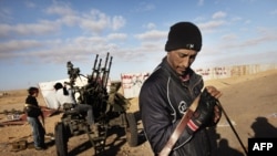 Rebel fighters man their antiaircraft guns in the town of Ras Lanouf today, as Libyan state television claimed that the city had been recaptured by loyalist forces.