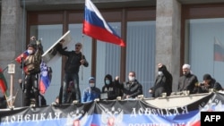 Pro-Russian activists who seized the main administration building in Donetsk wave a flag of the so-called Donetsk Republic and hold a Russian flag on April 7.