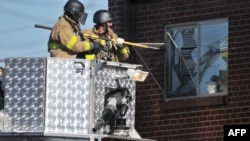 Police break the window at the apartment of James Holmes, the suspect of the deadly shootings.