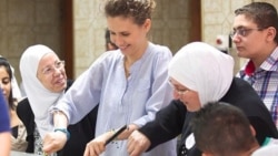 Smiling for the camera: the Syrian first lady preparing food for needy families during Ramadan.