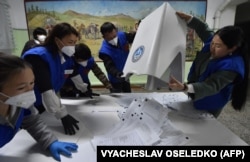 Members of a local election commission count votes at a polling station in the village of Gornaya-Mayevka, outside Bishkek, on October 4, 2020.