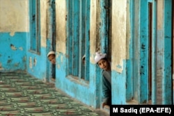 Afghan boys peek out inside a madrasah in Kandahar. "This is a major tragedy and amounts to a war on education. The Taliban's attitude towards education is destructive,” says one teacher about the Taliban's moves.