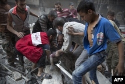 Syrians surround a man as he cries over the body of his child after she was pulled from the rubble of a building following air strikes by government forces in the rebel-held neighborhood of Al-Shaar in Aleppo on September 27.