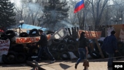 People walk past a barricade near the Ukrainian Security Service building in Luhansk occupied by pro-Russian activists on April 15.