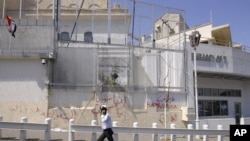 A policeman walks in front of the damaged U.S. embassy after pro-government protesters attacked the embassy and raised a Syrian flag on the compound in Damascus