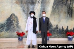 Chinese Foreign Minister Wang Yi (right) hosted a Taliban delegation in Tianjin, China, that was led by Taliban co-founder Mullah Abdul Ghani Baradar (left) on July 28.