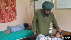 Abdul Ghaffar comforts his wounded child at a hospital in Kandahar on July 24.