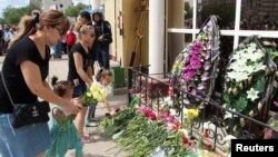 People place flowers outside a gun shop in memory of a salesman who was killed during the June 5 attacks in Aqtobe.