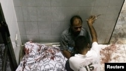 Men grieve next to the body of a relative who was among the victims of the attack on a Karachi market on October 19.