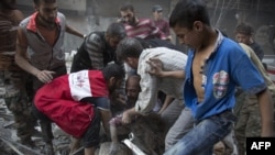 Syrians surround a man as he cries over the body of his child after she was pulled out from the rubble of a building following government air strikes in the rebel-held neighborhood of Al-Shaar in Aleppo on September 27.