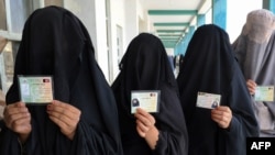 Burqa-clad women show ID cards as they wait to cast their votes in Kandahar. Is their willingness to participate a sign of Taliban weakness?