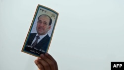 A man holds up an election pamphlet of Prime Minister Nuri al-Maliki during a speech in Karbala.