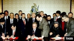 Tajik President Emomali Rahmon (left) and opposition leader Said Abdullo Nuri (right) sign an agreement on national reconciliation in Moscow in December 1996.