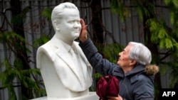 A woman touches a bust of the late Yugoslav President Slobodan Milosevic at his grave in the Serbian town of Pozarevac. (file photo)